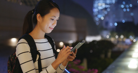 Woman using cellphone in city at nightの写真素材