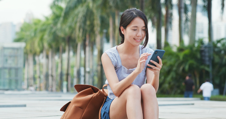 Woman looking at cellphone with the background of green plantの写真素材