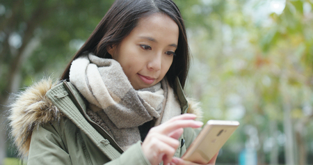 Woman sending text on cellphone at outdoorの写真素材