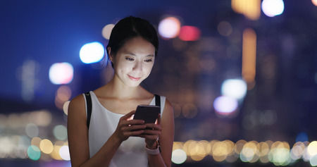 Woman send sms on mobile phone at nightの写真素材