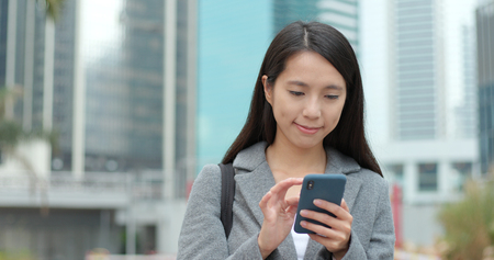 Businesswoman use of smart phone in Hong Kongの写真素材