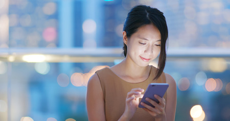 Woman look at the cellphone in the city at nightの写真素材