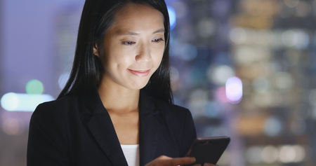 Young businesswoman use of cellphone at nightの写真素材
