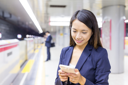 Businesswoman working on cellphone in train stationの写真素材