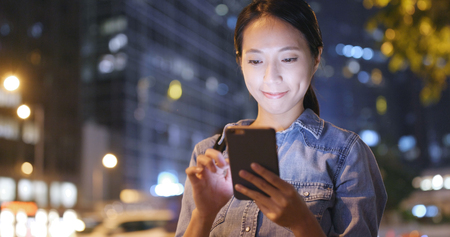 Woman using mobile phone with the background of Hong Kong cityの写真素材