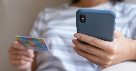 Woman using mobile phone with credit card for online shoppingの写真素材