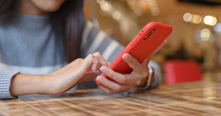 Woman using mobile phone in restaurantの写真素材