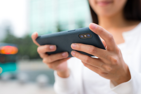 Woman playing game on cellphone at outdoorの写真素材