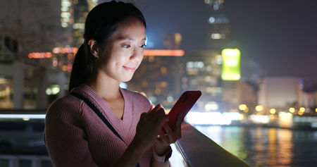 Woman use of smart phone in city at nightの写真素材