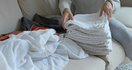 Woman fold white towel at home