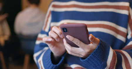 Woman play game on cellphone inside coffee shopの写真素材