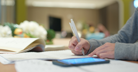 Woman write on the note for studying with cellphoneの写真素材