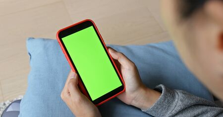 Woman use of mobile phone with green screen at homeの写真素材