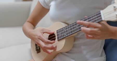 Woman practice ukulele at home