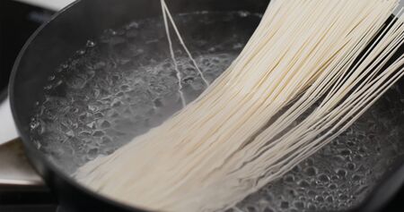 Cooking with noodle in skillet in the kitchenの写真素材