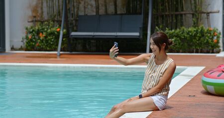 Woman take selfie on cellphone at pool sideの写真素材