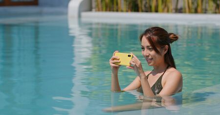 Woman take photo on cellphone in swimming pool