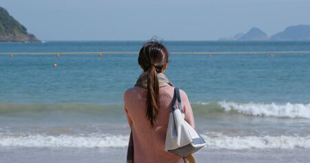 Woman looks at the sea at winter timeの写真素材