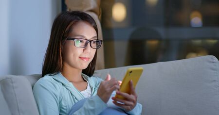 Woman with glasses and use of mobile phone at homeの写真素材