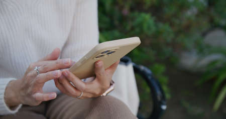 Woman use of mobile phone and sit at parkの写真素材