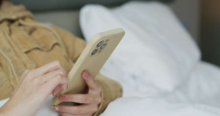 Woman touch on cellphone on bed
