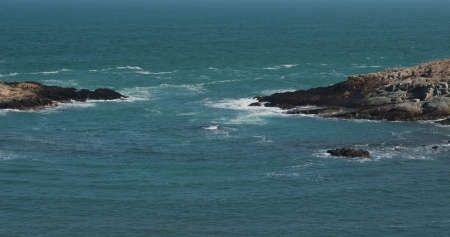 Big sea waves splash against rock on island