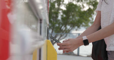 Woman using mobile phone to pay of vending machineの写真素材