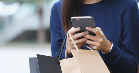 Woman use of mobile phone with shopping bagの写真素材
