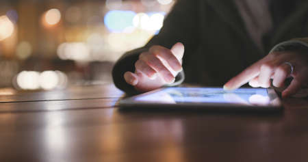 Woman using tablet computer in outdoor coffee shop at nightの写真素材