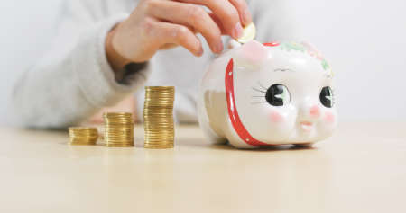 Putting golden coins into piggy bank