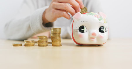 Putting golden coins into piggy bank at homeの写真素材