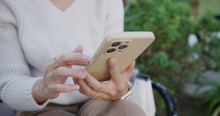 Woman use of mobile phone and sit at parkの写真素材