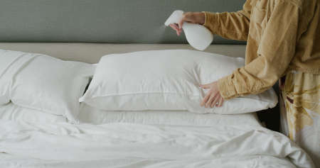 Woman use spray for clean the bed at homeの写真素材