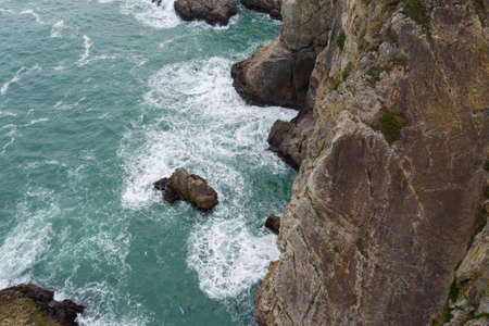 Ocean waves splash against rocksの写真素材