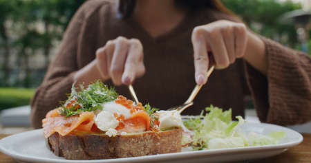 Woman eat salmon toast at outdoor cafeの写真素材