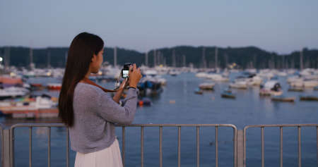Woman use camera to take photo on the pierの写真素材
