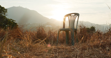 Sunset sunlight flare over the chair in tall grassの写真素材