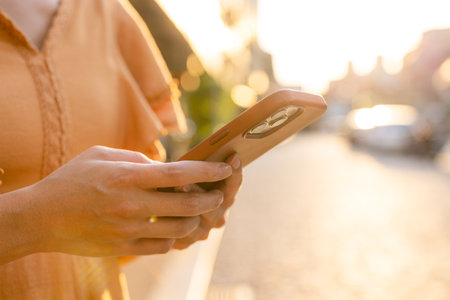 Woman use mobile phone at outdoor under sunlight flareの写真素材