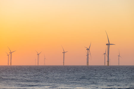 Large wind turbines producing plant on the sea under sunsetの写真素材