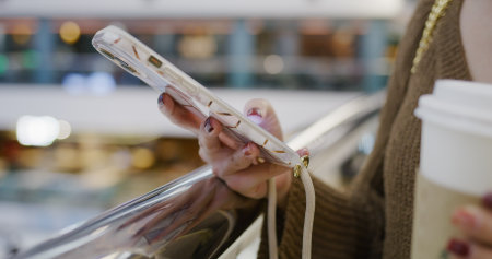 Woman use of mobile phone and hold with hot coffeeのeditorial素材