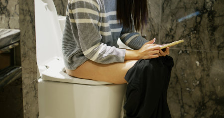 Woman use mobile phone at toiletの写真素材