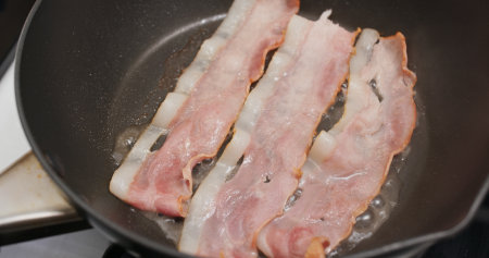 Fry bacon in pan in kitchen for breakfastの写真素材