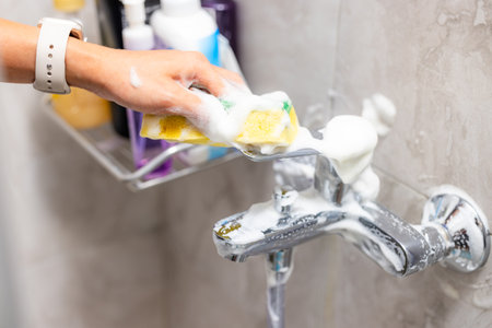 Cleaning hard water stains deposits on bath tap at toiletの写真素材