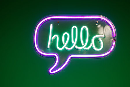 Green and purple neon lamp with word hello over the green wallの写真素材