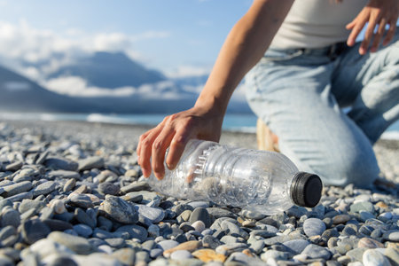 Woman hand picking up plastic bottle cleaning on the beachの写真素材