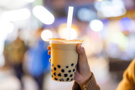 Asian woman holding the famous taiwanese bubble milk tea at night marketplaceの写真素材