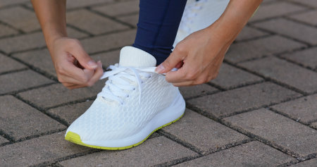 Young adult female tying shoe lace before a runの写真素材