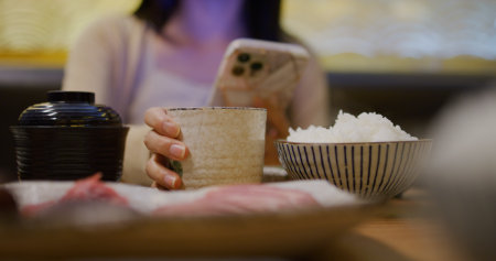 Woman using smart phone in restaurantの写真素材