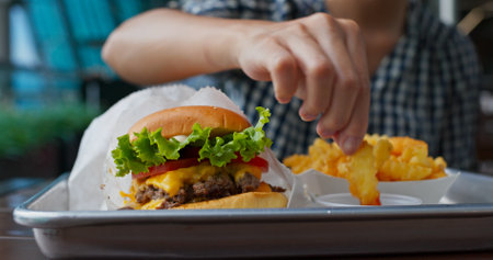 Woman enjoys burger and French friesの写真素材