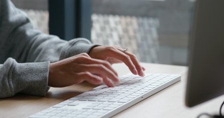 Woman type on desktop computerの写真素材